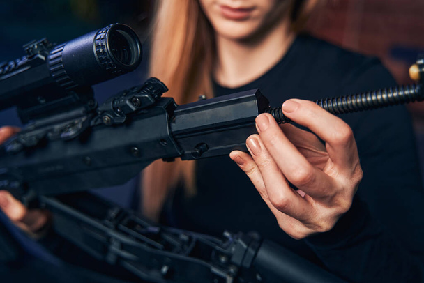 Experienced blonde female shooter assembling an assault rifle - Photo, Image