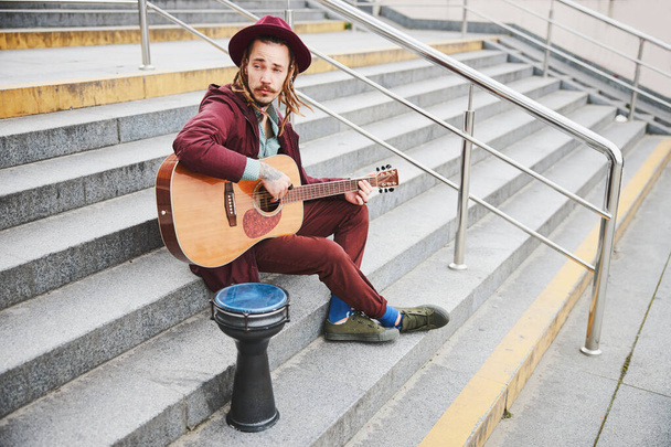 Kind hippie sitting on stairs with guitar - Photo, Image