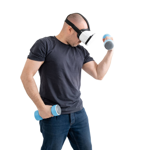 Unsportsmanlike middle-aged man wearing virtual reality glasses with dumbbells. Isolated on a white background. - Foto, imagen