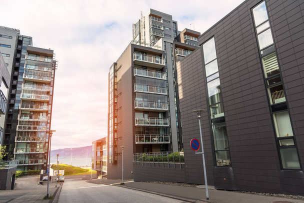Új toronyház vízparti apartman épületek elválasztva egy utcával naplementekor. Reykjavik, Izland. - Fotó, kép