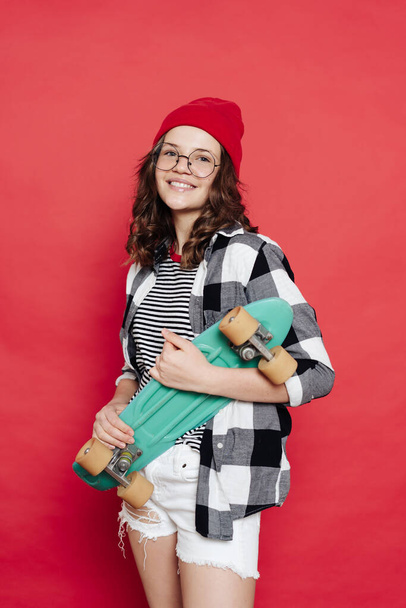Hermosa adolescente posando con tablero de penique sobre fondo rojo - Foto, imagen