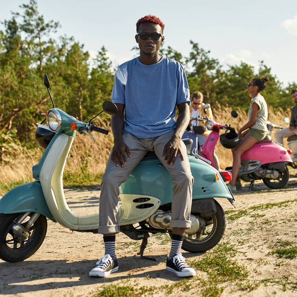 Happy young african american boy resting on retro scooter - 写真・画像