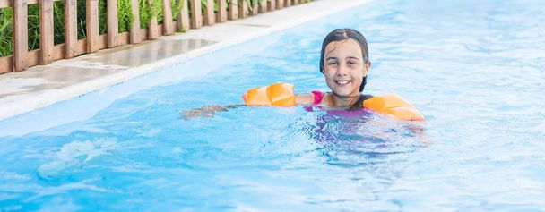 Bella bambina nuotare in piscina all'aperto e divertirsi - Foto, immagini