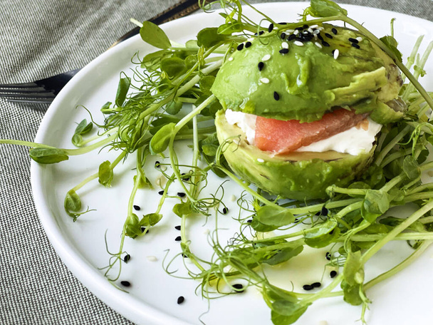 avocado with salmon and pea sprouts on a plate - Photo, Image