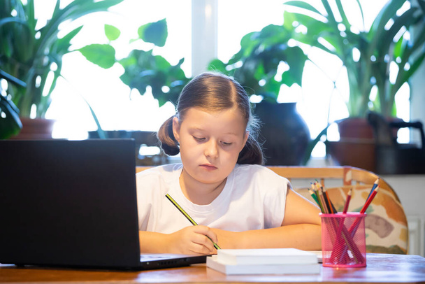 Distance learning, online education. School girl watching online education classes and doing school homework. COVID-19 pandemic forces children online learning. - Foto, afbeelding