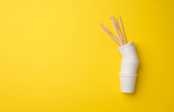 stack of white paper cups on a yellow background. Plastic rejection concept, zero waste, copy space - Photo, Image