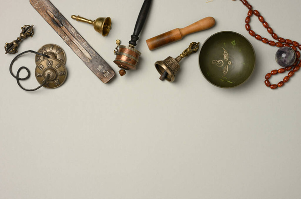 Cuenco de cobre tibetano cantor con una palmada de madera sobre un fondo gris, objetos para la meditación y la medicina alternativa, vista superior, espacio de copia - Foto, imagen