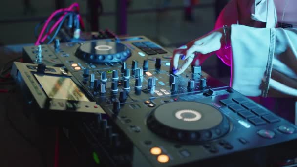 Közelről. DJ hangvezérlő konzol tánczene keveréséhez a diszkó klubban. Kezek érintése gombok csúszkák, játszik elektronikus zenét keverő fedélzeten, színes megvilágítás nightclub tánc party. - Felvétel, videó