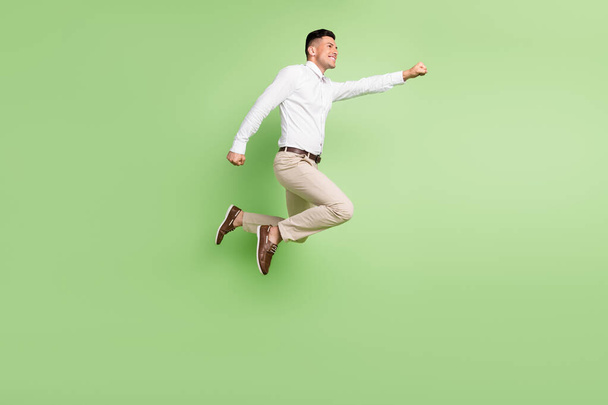 Full length photo of cute funny gentleman wear white shirt smiling jumping high looking empty space isolated green color background - Fotografie, Obrázek