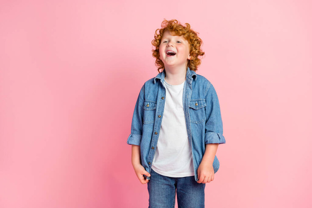 Photo of crazy playful glad nice little boy look empty space wear denim jacket isolated pink color background - Фото, изображение