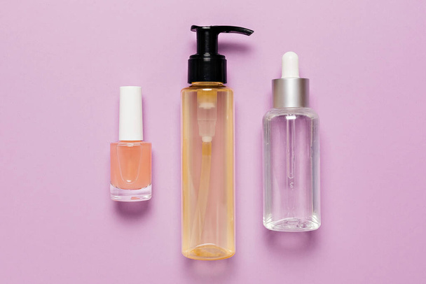 Organic cosmetics packaging design. Flat lay, top view clear glass pump bottle, brush jar, moisturizing serum jar on a purple background. Natural cosmetics SPA - Foto, immagini