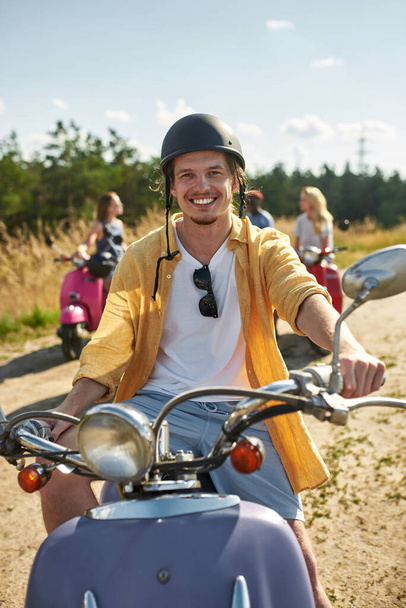 Cheerful young caucasian man resting on retro scooter - Photo, image