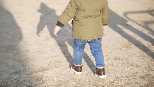un petit enfant bien formé marche sur le sol à l'extérieur - Photo, image