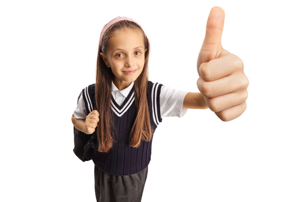 Smiling schoolgirl gesturing a thumb up sign isolated on white background - Fotó, kép