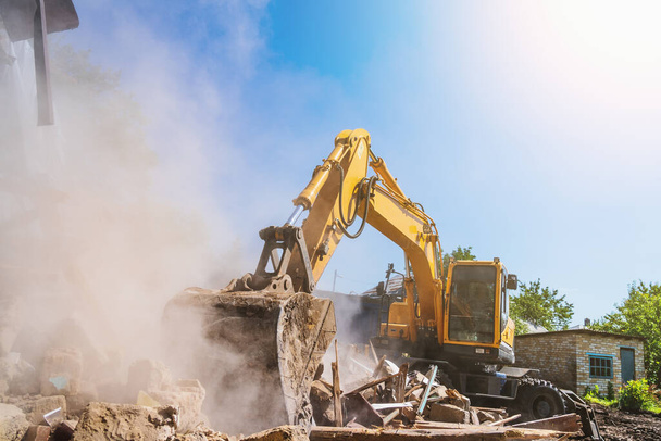Excavator breaks old house, many dust in air. Building demolition and deconstruction, copy space - Photo, Image