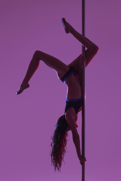 Young beautiful brunette girl doing pole dancing exercise. isolated - Фото, зображення