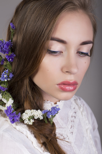 όμορφη μελαχρινή κοπέλα με φυσικό μακιγιάζ και λουλούδια στα μαλλιά - Φωτογραφία, εικόνα
