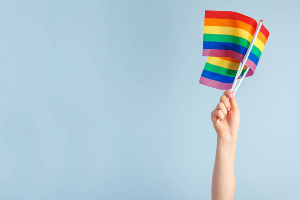Gay flags in womens hand on grey background - Foto, Imagen