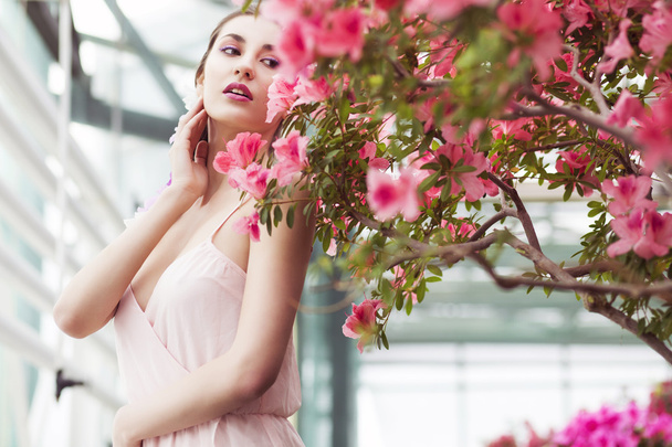 Portrait of a beautiful brunette woman in pink dress and colorful make up outdoors in azalea garden. Copy Space - Foto, afbeelding