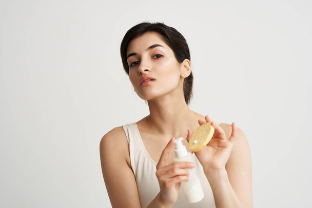 femme en t-shirt blanc applique une lotion sur une éponge peau propre - Photo, image