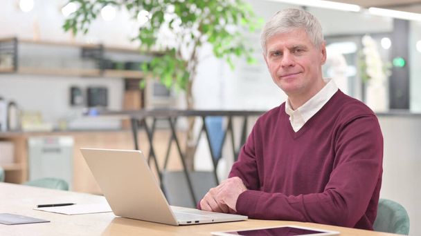 Serious Middle Aged Businessman with Laptop Looking at the Camera - Photo, Image