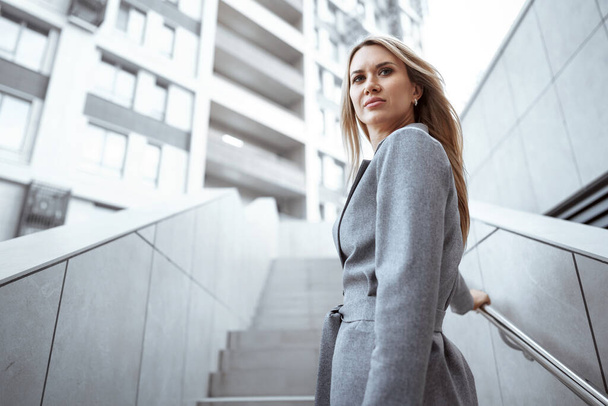 Portrait of young blonde businesswoman in gray suit walking in the city - Foto, Bild