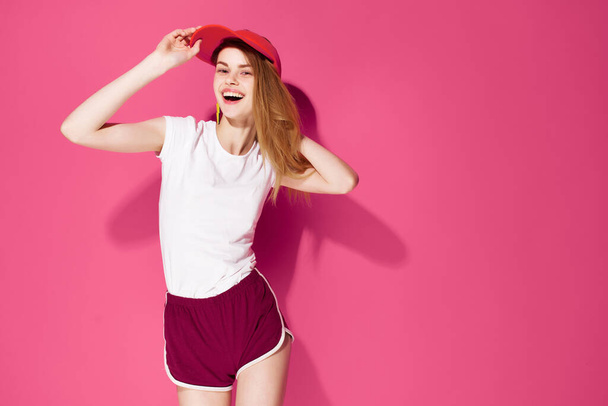 明るい女性ですホワイトtシャツとショートパンツポーズ夏ピンクの背景 - 写真・画像
