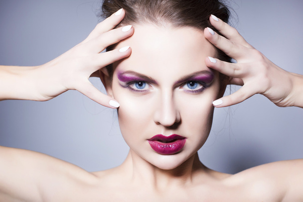 Bella donna bruna con trucco creativo ombretti viola labbra rosse piene, occhi blu e capelli ricci con la mano sul viso
 - Foto, immagini