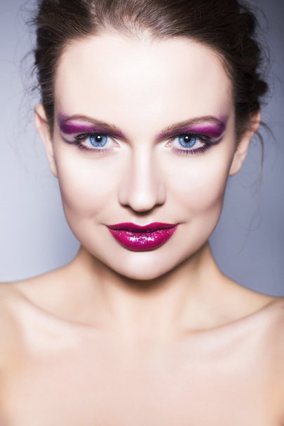Kaunis brunette nainen luova muodostavat violetti luomivärejä täynnä punaiset huulet, siniset silmät ja kiharat hiukset
 - Valokuva, kuva