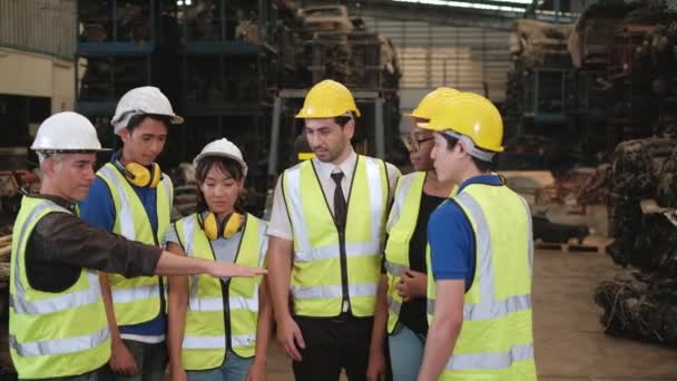 Un groupe de personnes en uniformes et casques dans l'entrepôt : Les travailleurs de diverses races telles que caucasiens, noirs et asiatiques sont des employés d'usine et des collègues collaborant et en harmonie dans l'entreprise. - Séquence, vidéo