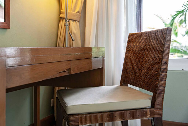 Hnědá ratanová židle a dřevěný make-up stůl v moderní ložnici - Fotografie, Obrázek