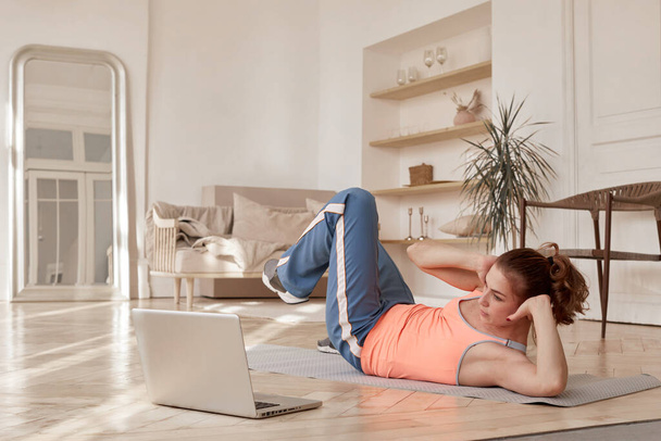 Femme faisant du sport devant un ordinateur portable à la maison - Photo, image