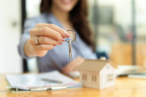Kobieta pośrednik mieszkaniowy, agent nieruchomości posiadający klucze do domu w ręku, koncepcja inwestycji nieruchomościowych - Zdjęcie, obraz