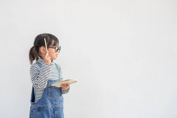 Aranyos ázsiai kislány visel szemüveg és gondolkodás - Fotó, kép