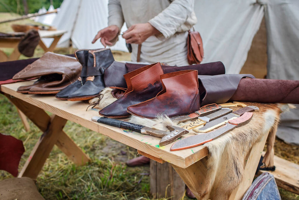 A kézműves cipész bemutatja a cipőket, szerszámokat és bőrt a suszter munkahelyen a fesztiválon - Fotó, kép