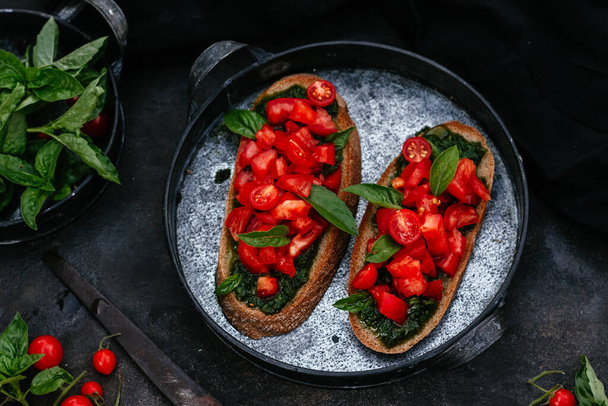  sandwiches with pesto and tomatoes on black bread on a dark background - Valokuva, kuva