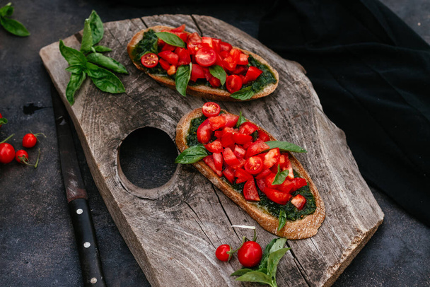  sanduíches com pesto e tomates em pão preto em um fundo escuro - Foto, Imagem
