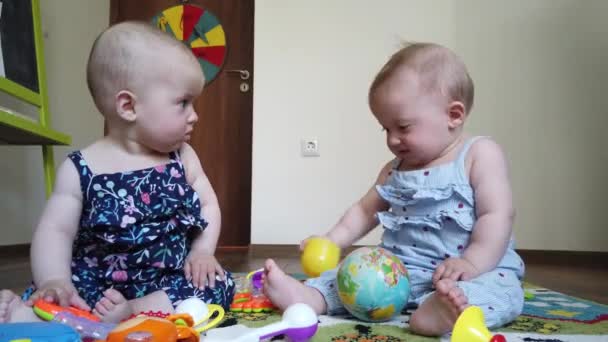 broederlijke tweeling meisjes zussen, spelen met speelgoed op de vloer thuis - Video