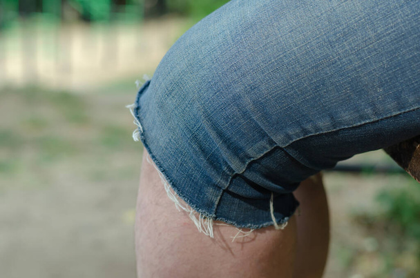 Gros plan du genou d'une femme adulte. Femme assise en short en denim bleu dehors. Concentration sélective. - Photo, image