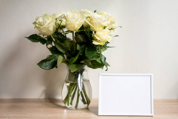 Portret biały ramka makieta na drewniany stół. Nowoczesny wazon z różami. Wysokiej jakości zdjęcie - Zdjęcie, obraz