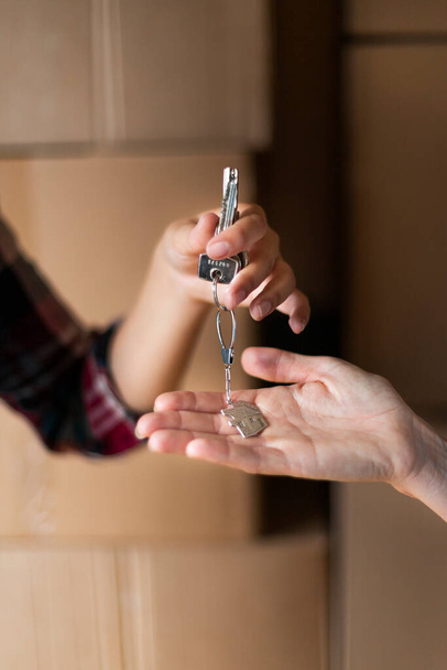 New home. Close up of hands giving house keys to new owners. First time owners receive house keys. Relocation concept. - Foto, Bild