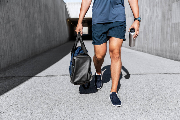sportsman with bag and bottle walking outdoors - 写真・画像