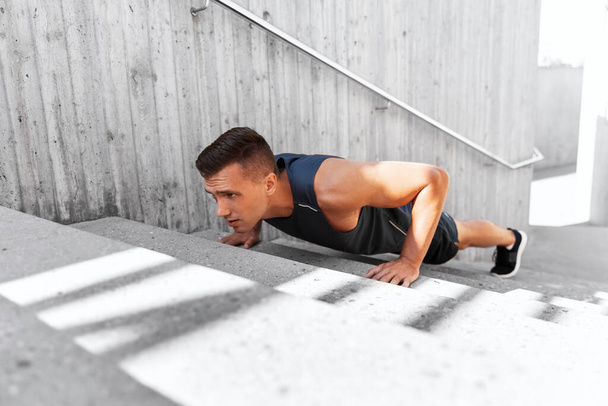 young man doing push ups on stairs outdoors - 写真・画像
