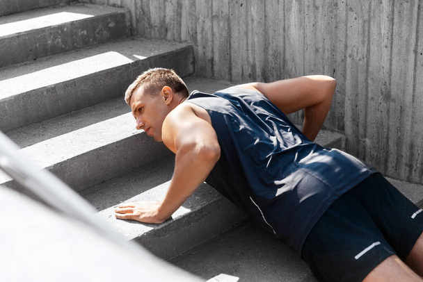young man doing push ups on stairs outdoors - Valokuva, kuva