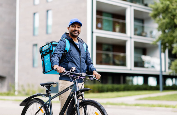 indian delivery man with bag and bicycle in city - Photo, image