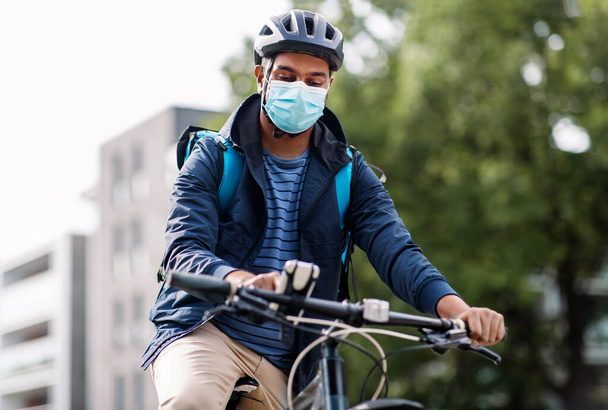 чоловік доставки в масці з смоктати телефон їзда на велосипеді
 - Фото, зображення