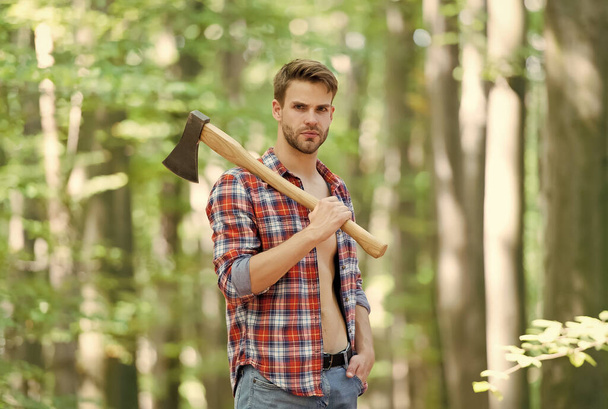lumberjack in forest holding an axe on his shoulder, nature - Zdjęcie, obraz
