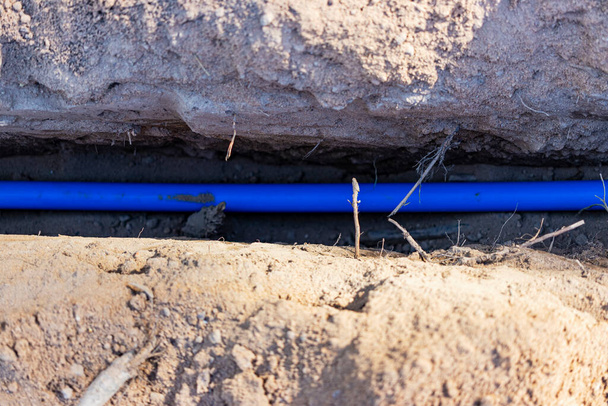 Colocando um cabo elétrico azul em uma trincheira no chão. Comunicações subterrâneas. Trabalhos eléctricos no estaleiro - Foto, Imagem