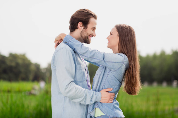 Profile side photo of two people lovely smiling couple hug embrace each other admire free time together outdoors in park - Fotó, kép