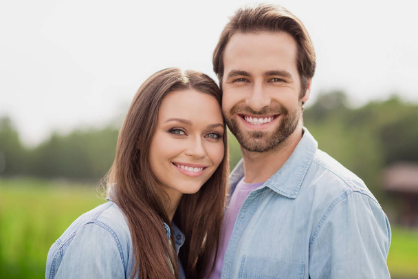 Фотопортрет молодая пара улыбается прогуливаясь в зеленом городском парке в синих джинсовых куртках - Фото, изображение